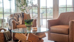 A modern living room with a glass coffee table, leather armchair, and a potted plant. - Bella Vista - A Quiet Lakeside Escape on 30A (Seacrest)