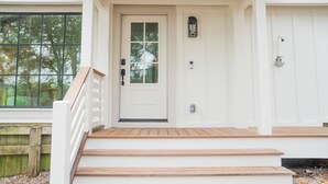 A white front door with a glass panel, a wooden staircase leading up to a porch, and a small outdoor light fixture above the door. - Bella Vista - A Quiet Lakeside Escape on 30A (Seacrest)