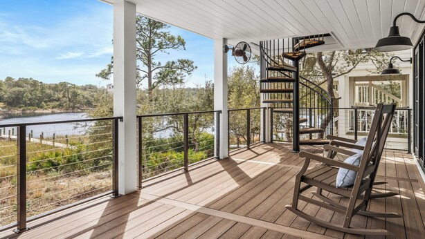 A wooden deck with a view of a lake and trees, a rocking chair, and a spiral staircase. - Bella Vista - A Quiet Lakeside Escape on 30A (Seacrest)