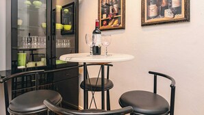 Un comedor con una mesa, sillas, un mueble con puertas de vidrio y cuadros en la pared.