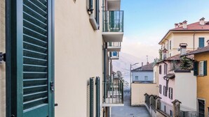 Eine schmale Stadtstraße mit Häusern an beiden Seiten, einem Metallgeländer und blauem Himmel.