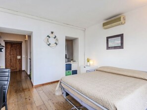Ein Schlafzimmer mit einem Bett, einem Schreibtisch, einem Stuhl, einem Kleiderschrank und einer Tür.