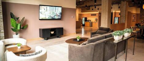 A modern lounge area with sofas, a coffee table, a TV, and a kitchen in the background.