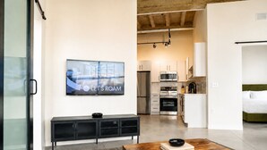 Una sala de estar moderna con una televisión de pantalla plana, una mesa de centro de madera y un sofá.
