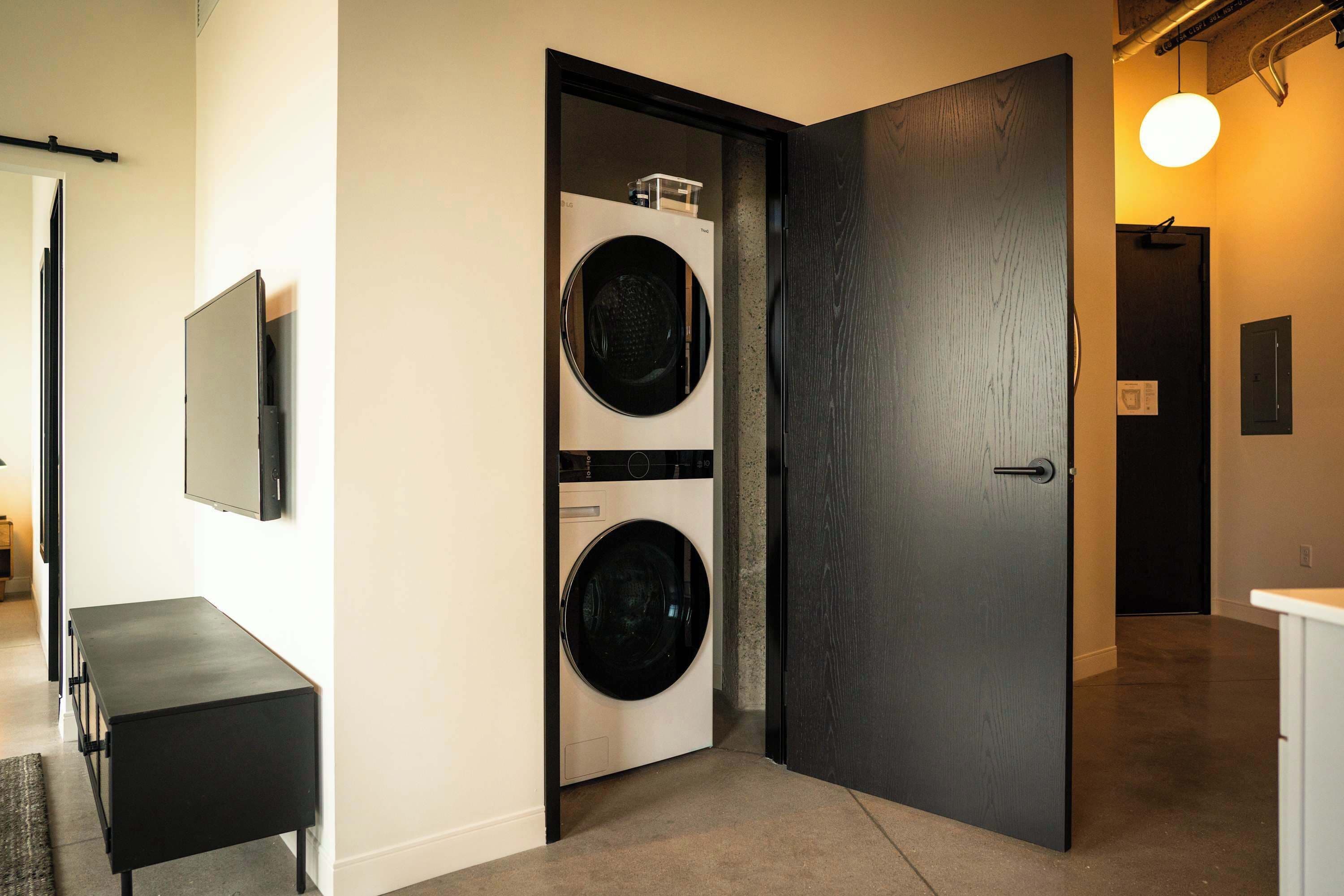 A laundry room with two washing machines, a door, and a bench.