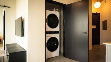 A laundry room with two washing machines, a door, and a bench.
