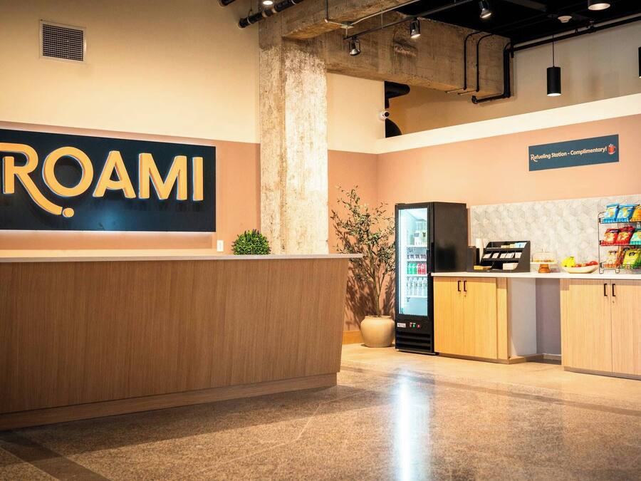 Een receptiegedeelte met een groot ROAMI-bord, een tankstation, een koelkast en een snackbar.