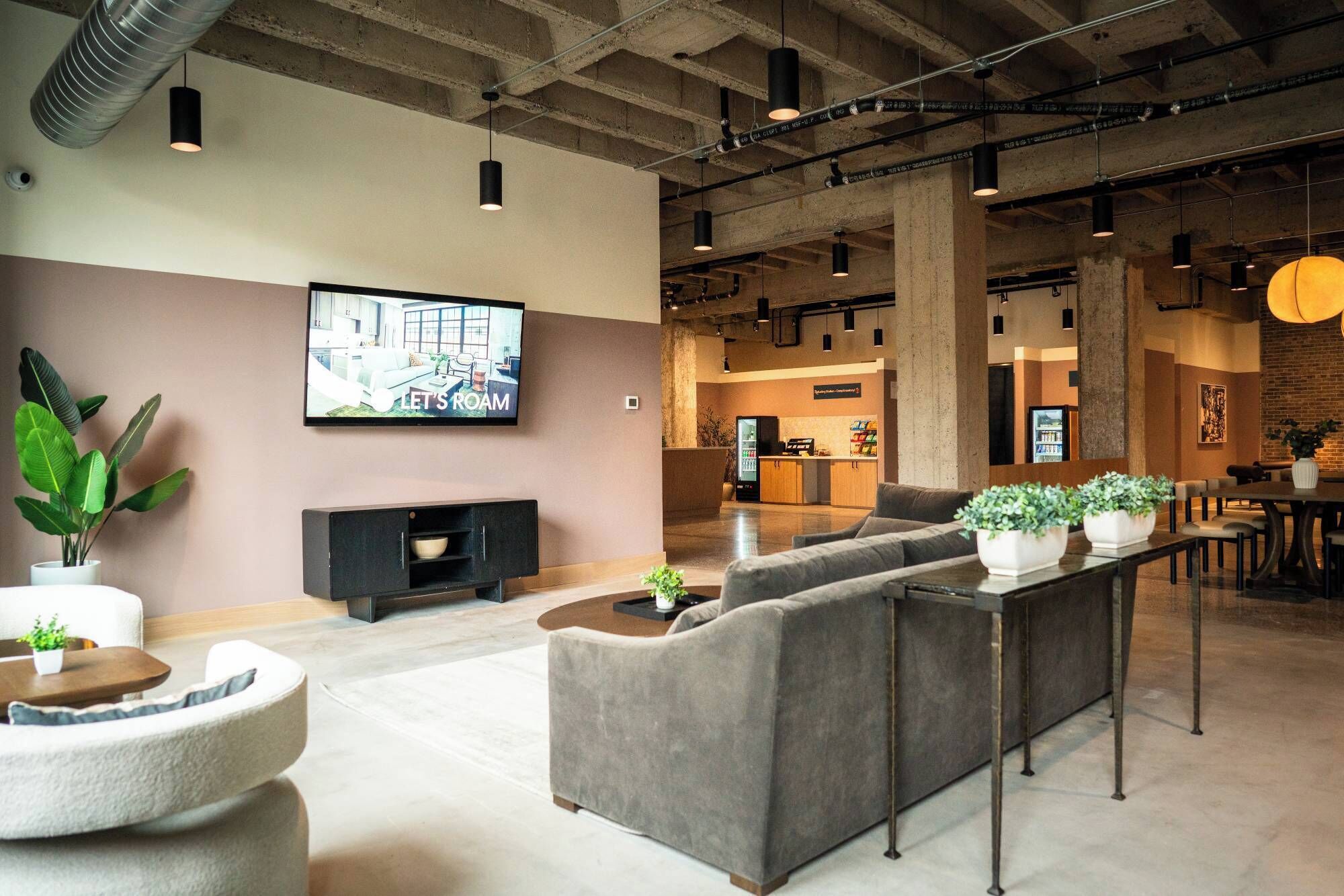 A modern lounge area with sofas, a TV, and a kitchen in the background.