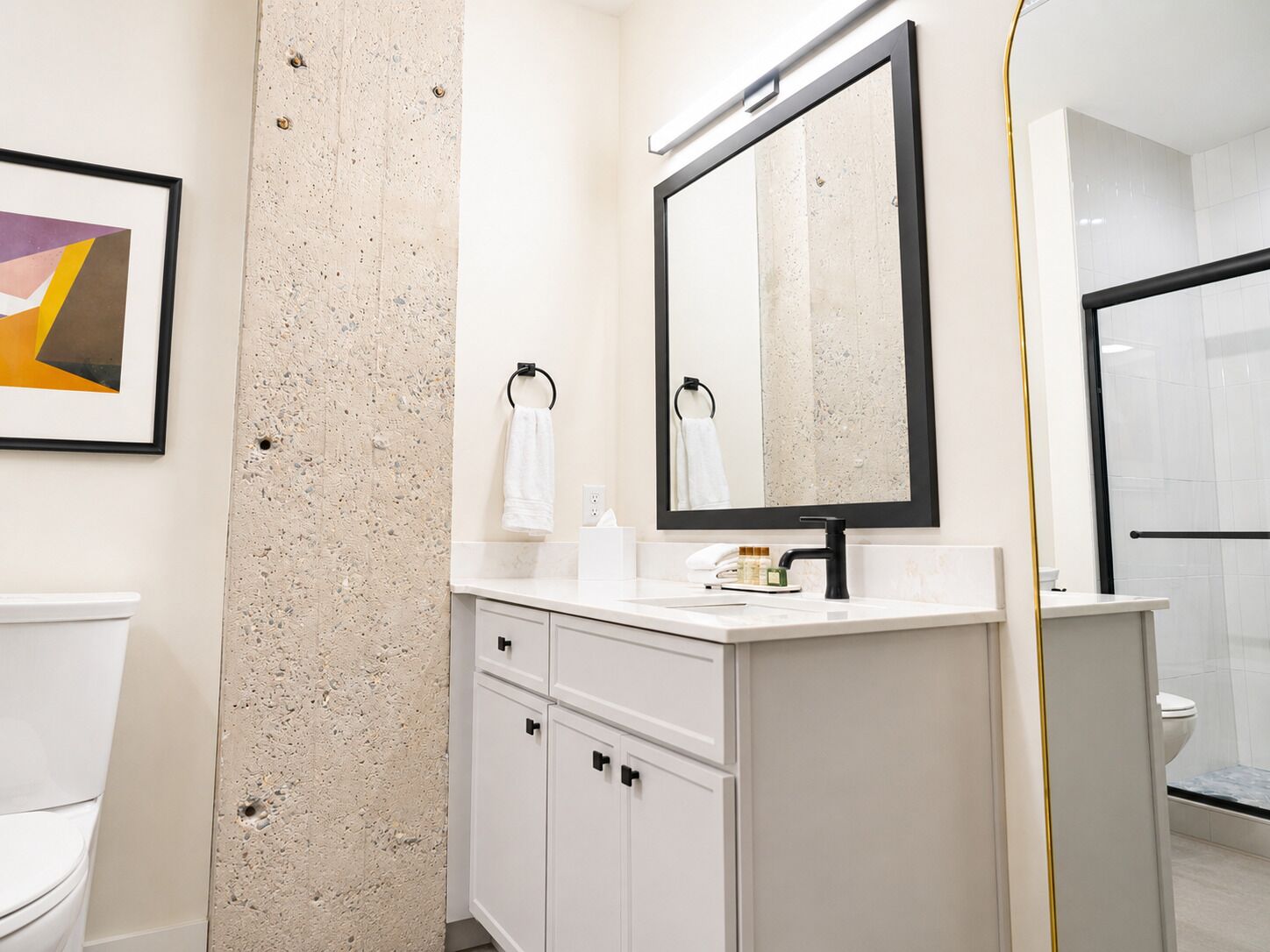 A bathroom with a white toilet, a sink with a mirror, and a shower area.