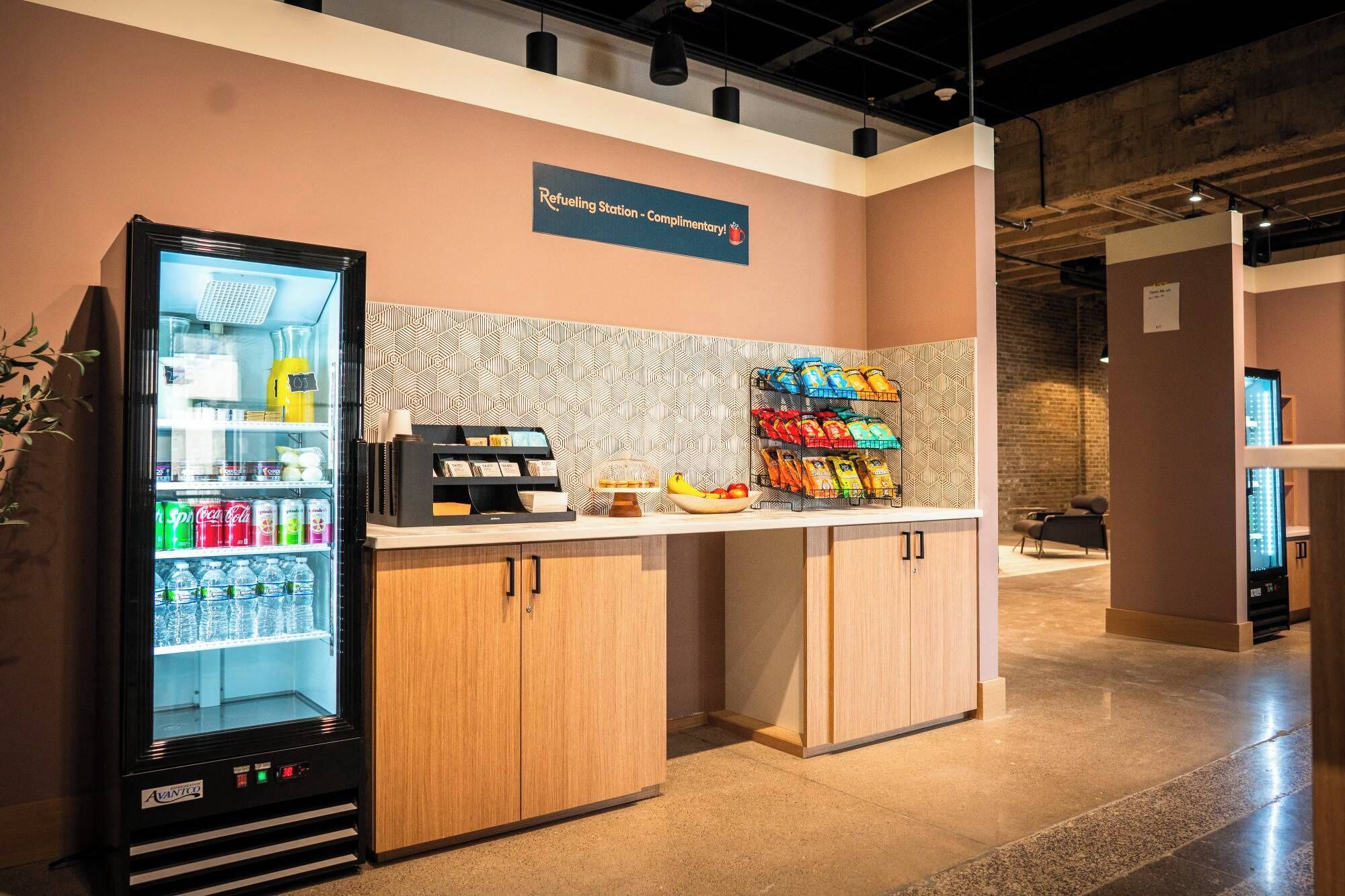 A refueling station with a Coca-Cola refrigerator, a coffee machine, and snack dispensers.