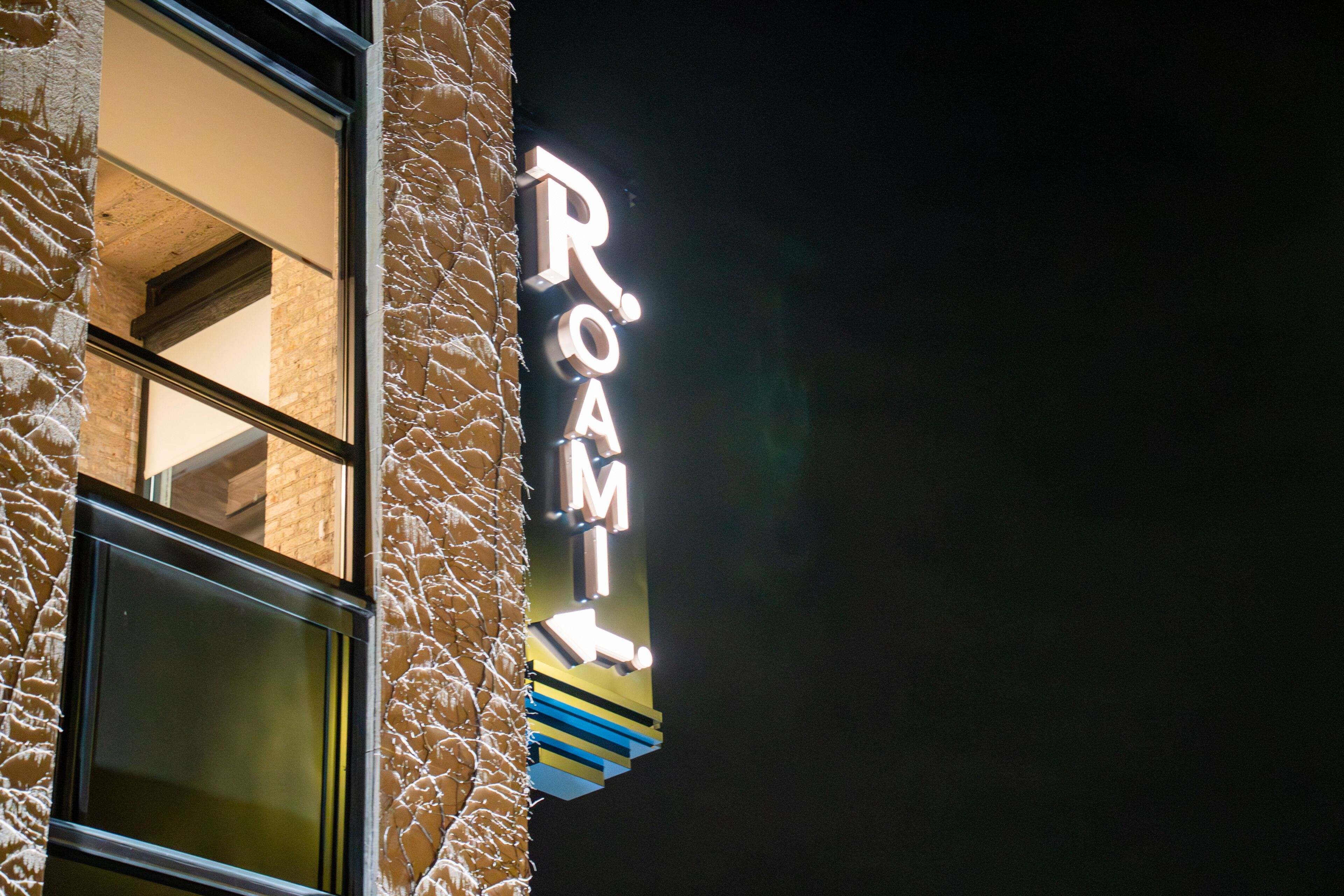 A building with a neon sign that reads 'ROOM' on the side.