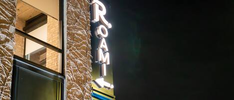 A building with a neon sign that reads 'ROOM' on the side.