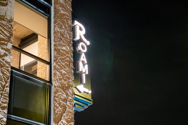 En byggnad med en neonskylt på sidan där det står ”RUM”.