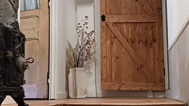 A wooden staircase leading to a door with a cross-brace design.