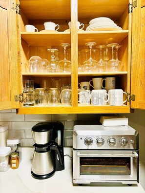 Een keuken met houten kastjes, een koffiezetapparaat en een oven.