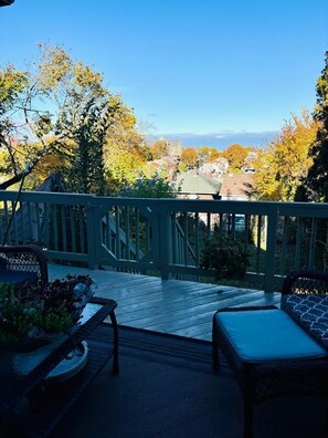 A deck with a view of a town, a bench, and a table with plants. - Energetic Oasis 3 Bedroom 1 Full Bath Covered Front Porch (Dormont)