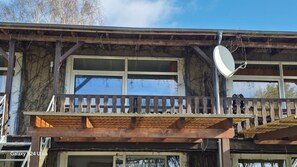 A wooden balcony with a satellite dish, large windows, and a visible garage door. - Mobile Home im Ferienpark mit Seezugang (Dabel)