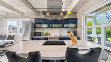 Una cocina moderna con una isla central, electrodomésticos de acero inoxidable y ventanas amplias.