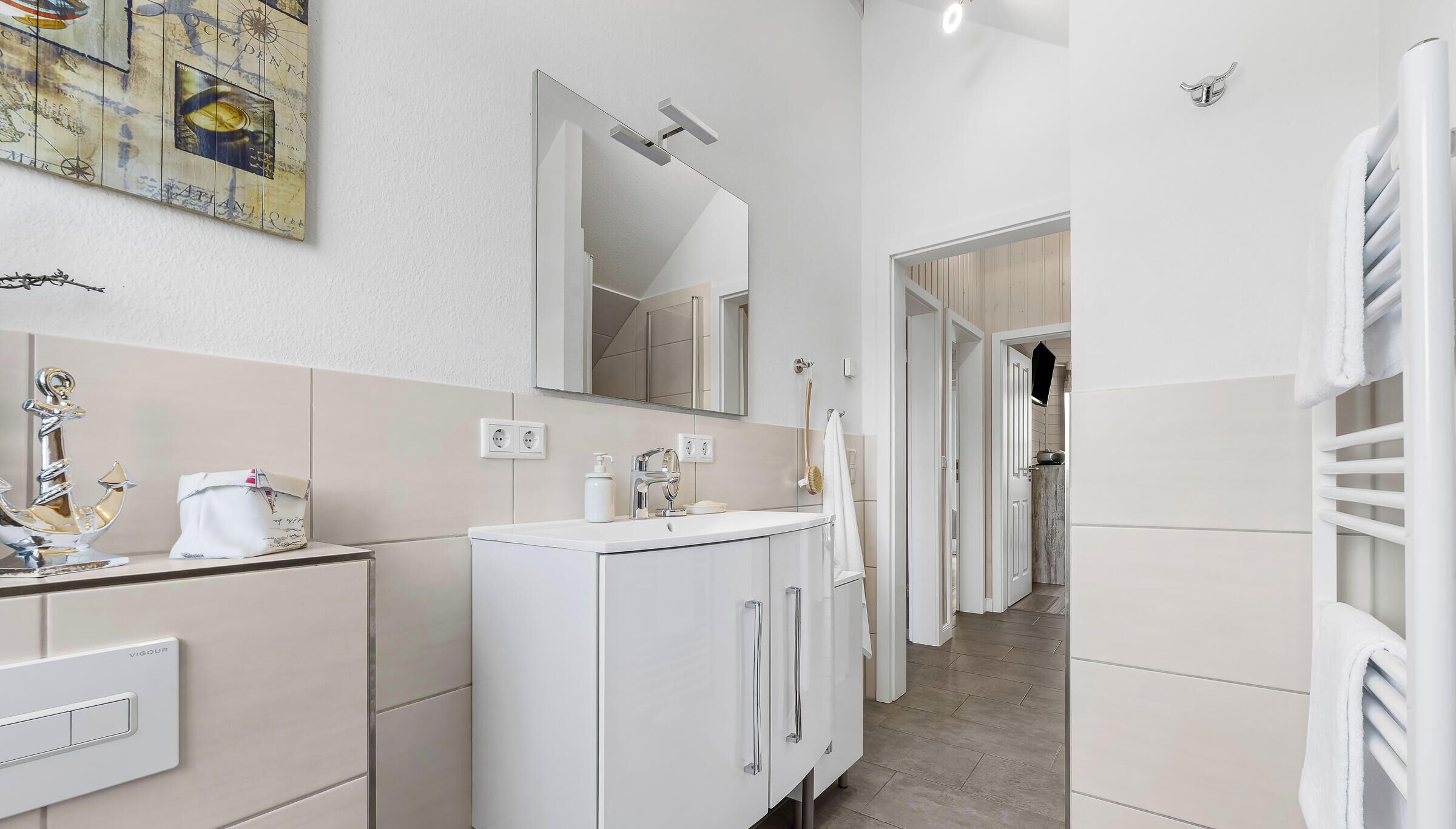 Ein modernes Badezimmer mit Waschtisch, Spiegel und Handtuchhalter.
