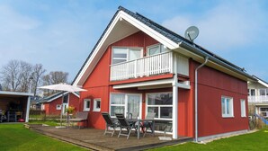 A two-story house with a balcony, a deck, and a satellite dish. - Ferienhaus "Plüschmors" in Schönberg-Holm: Sauna, Kamin, 600 m Strand, Strandkor (Schönberg (Holstein))
