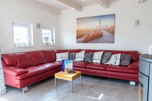 En rød lædersofa, et træbord og et maleri af et fyrtårn på væggen.