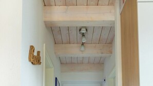 A hallway with a wooden ceiling, a white door at the end, and a light fixture above. - Ferienhaus "Plüschmors" in Schönberg-Holm: Sauna, Kamin, 600 m Strand, Strandkor (Schönberg (Holstein))
