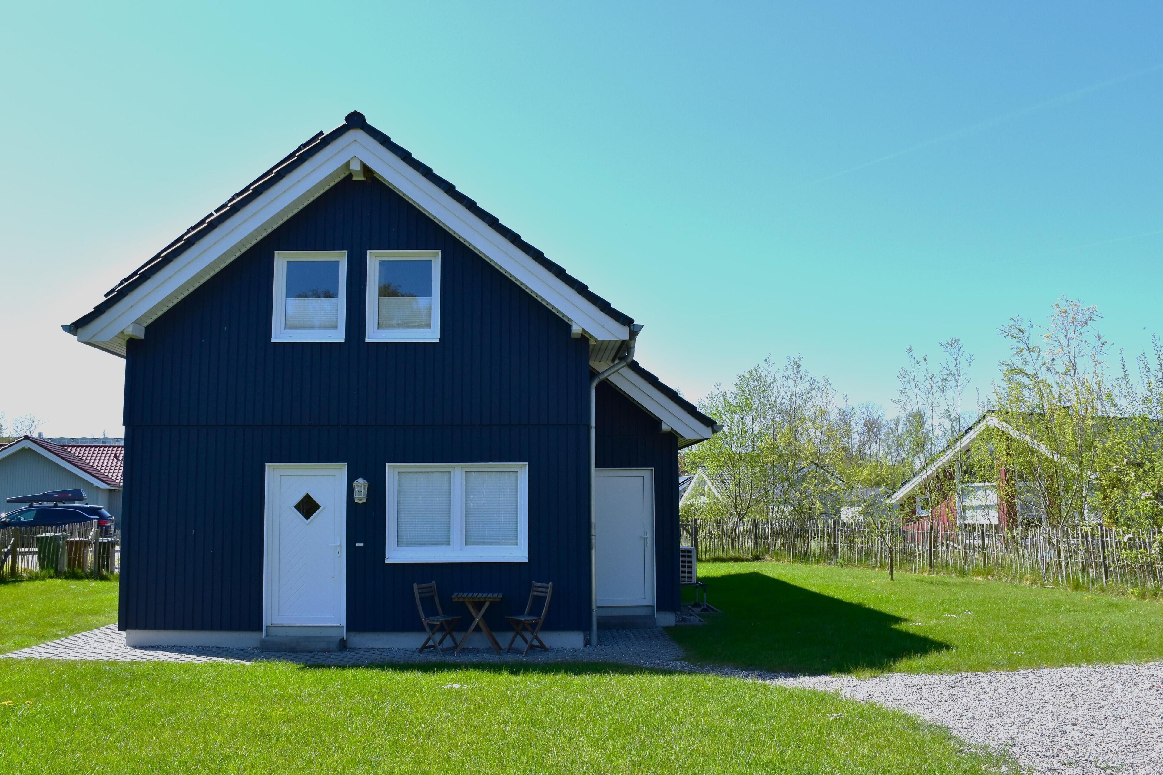 Une maison à deux étages, à l’extérieur sombre, avec une porte d’entrée, deux fenêtres et une porte de garage.