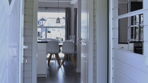 A hallway with white walls and a dark floor, leading to a dining area with chairs and a table. - Family Holiday Home with Sauna near the Sandy Beach in Schönberg-Holm (Schönberg (Holstein))