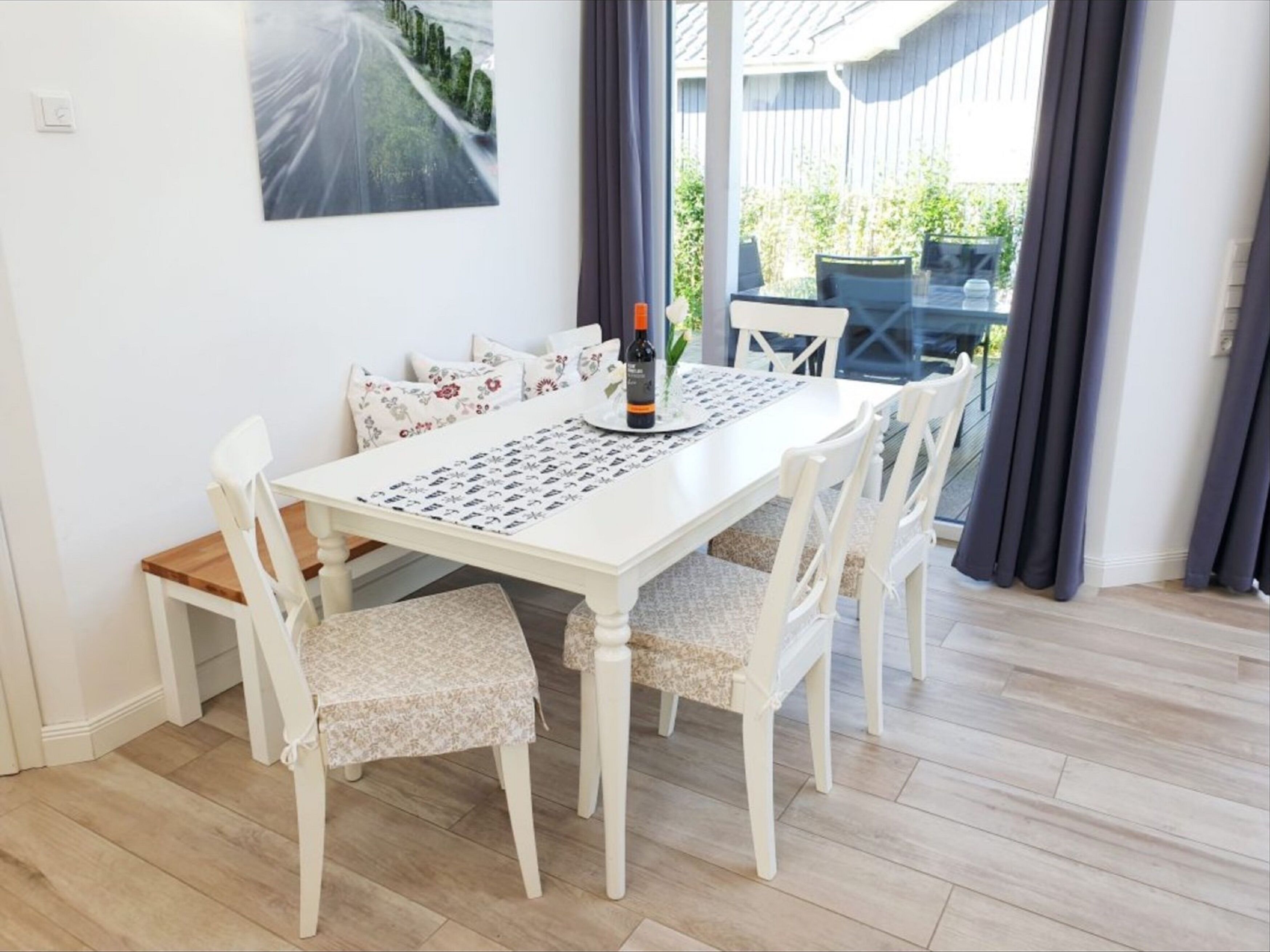A dining area with a white table, chairs, and a patterned table runner.