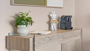 Ein Holzkonsolentisch mit einem Blumentopf, einer weißen Figur und einer Kaffeemaschine.