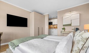 A hotel room with a bed, a TV, a kitchenette, and a bathroom. - Ferienwohnung Margaritha in List auf Sylt mit Meerblick und direkt am Strand (List auf Sylt)