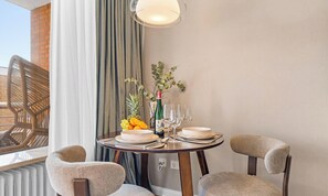 A dining area with a round table set for two, a bottle of wine, and a fruit bowl. - Ferienwohnung Margaritha in List auf Sylt mit Meerblick und direkt am Strand (List auf Sylt)