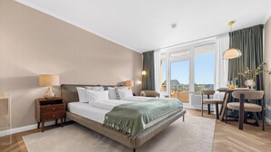 Ein Hotelzimmer mit Bett, Schreibtisch, Stuhl, Blick ins Freie und einem Balkon.