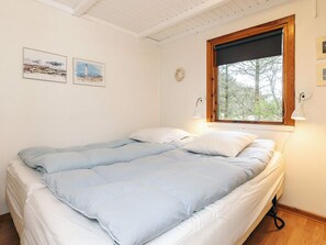 A bedroom with a bed, two wall-mounted lamps, a window with a view of trees, and two framed pictures on the wall. - 4 Star Holiday Home in Lokken (Lokken)
