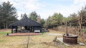 Un rustico chalet con veranda in legno e vasca idromassaggio.