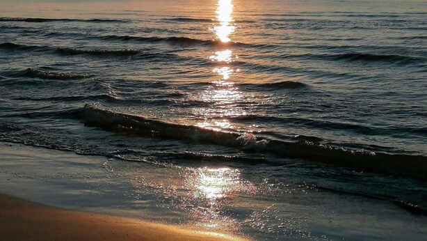 Tramonto sul mare calmo, con onde leggere.