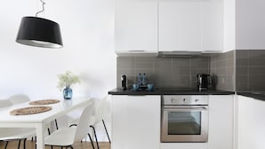 A modern kitchen with white cabinets, a black countertop, and stainless steel appliances. - Malila Apartments City Center Pawia 34 (Kraków)
