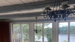 Une pièce chaleureuse avec un plafond en bois, de grandes fenêtres, un canapé, une table et une chaise.