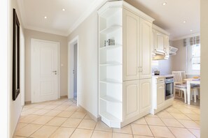 A kitchen with white cabinets, a stove, and a dining area with chairs. - Appartement La Mer am Strand in List auf Sylt (List auf Sylt)