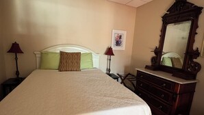 Une chambre à coucher avec un grand lit, une commode, un miroir et une table de chevet avec des lampes.