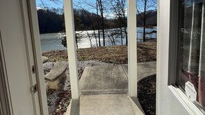 Un porche abrité avec un paillasson, une vue sur un lac et un banc.