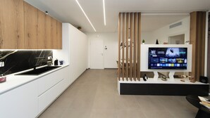 A modern kitchen with a built-in TV, wooden cabinets, and a white countertop. - Suite 20five, Romantic Suite with In-Room Jacuzzi Hot Tub. (Bari)