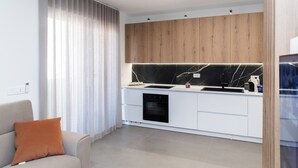 A modern kitchen with white cabinetry, a black marble backsplash, and wooden upper cabinets. - Suite 20five, Romantic Suite with In-Room Jacuzzi Hot Tub. (Bari)