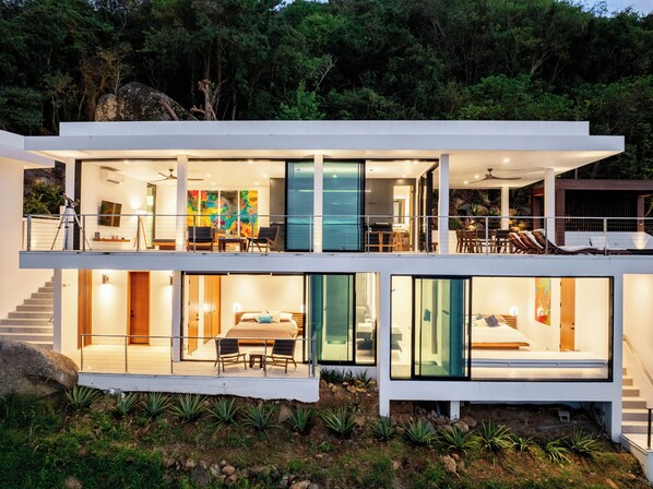 Une maison moderne à deux étages, dotée d’un balcon, d’un coin repas et d’une chambre.