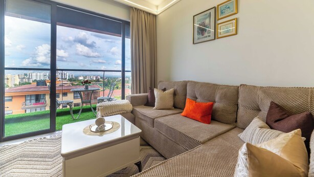 Ein modernes Wohnzimmer mit großem Fenster, einer Couch, einem Couchtisch und Blick auf einen Balkon.
