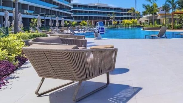 Un espace aménagé au bord de la piscine, avec des chaises longues, une piscine et un bâtiment en arrière-plan.