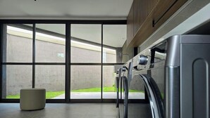 Une buanderie moderne avec de grandes fenêtres, un lave-linge et un sèche-linge.