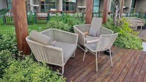 Un espace extérieur aménagé avec des meubles en osier et de la verdure.