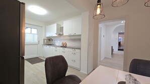 A modern kitchen with white cabinets, a black faucet, and a dining area with a table and chairs. - Beachfront vacation apartment "Ostseebrise" in Wendtorf with fenced garden - Hun (Wendtorf)