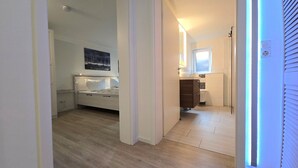 A bedroom with a bed, a nightstand, a wall-mounted lamp, and a painting. - Beachfront vacation apartment "Ostseebrise" in Wendtorf with fenced garden - Hun (Wendtorf)